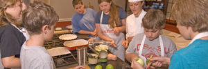 Kids participating in a cooking class hosted by a professional chef.