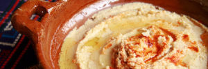 A terra cotta bowl full of home made hummus.