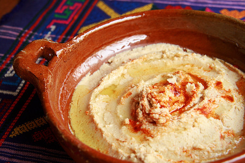 A terra cotta bowl full of home made hummus.