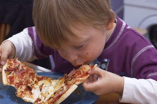 A young child enjoying a slice of pizza at a local pizzeria.