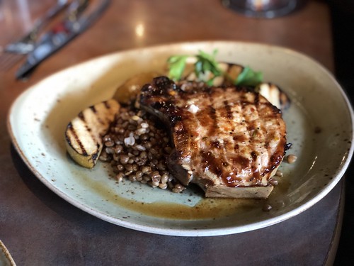 A plate full of delicious looking food including quinoa and a grilled pork chop.