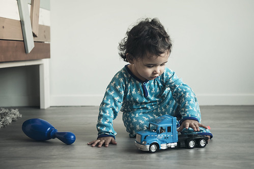 A toddler playing with trucks on the floor.