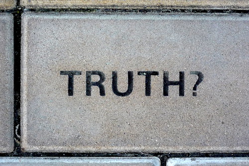 "TRUTH?" engraved in a gray concrete block.