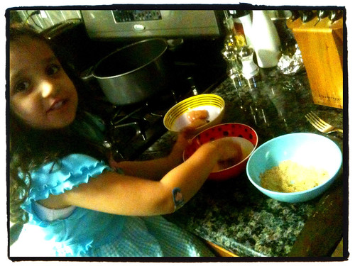 A small girl at the kitchen counter helping to make chicken nuggets.