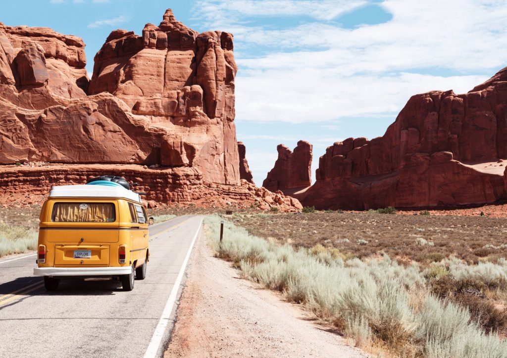 A yellow microbus driving through arches national park.