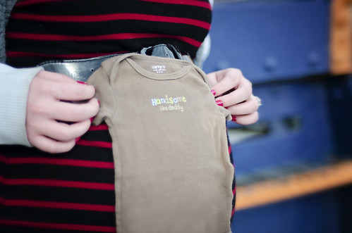 A pregnant mother holding an infant onesies for her new child.