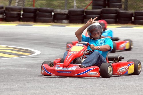 A young boy having fun driving a go kart around a go cart track.