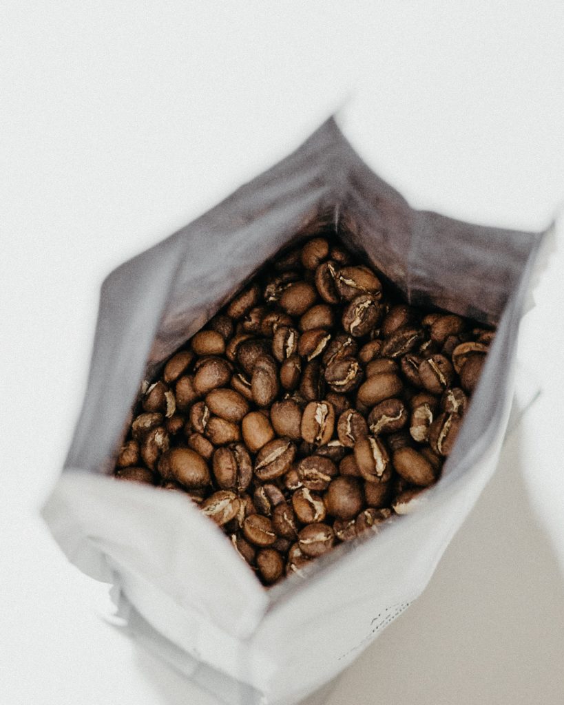 An open bag of whole, roasted coffee beans.