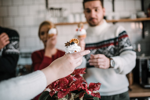 A woman handing a man a lemon muffin during a Christmas party.