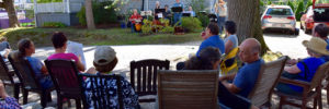 A few Carmel, IN. families sitting on the sidewalk while a local sextet during Porchfest.