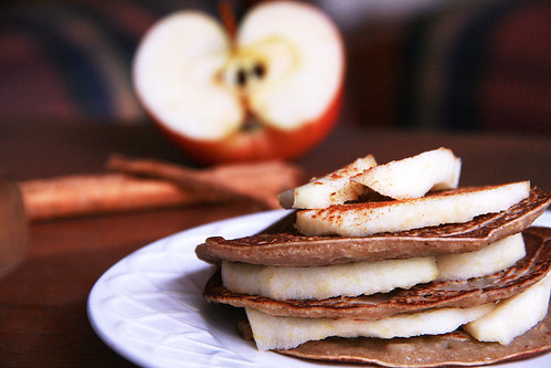 Freshly made pancakes covered with cinnamon dusted apple slices.