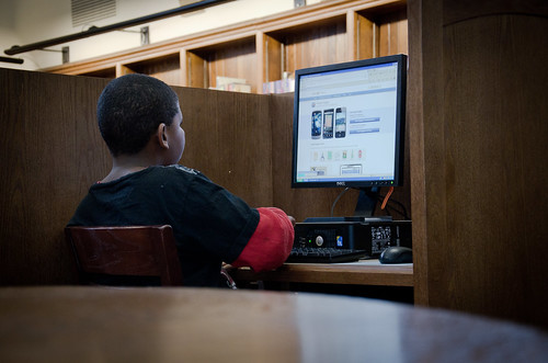 A middle-school boy working at a computer in his local library.