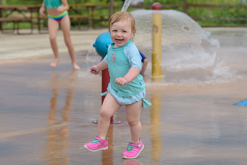 A small girl enjoying a hot summer day at a local splash pad.