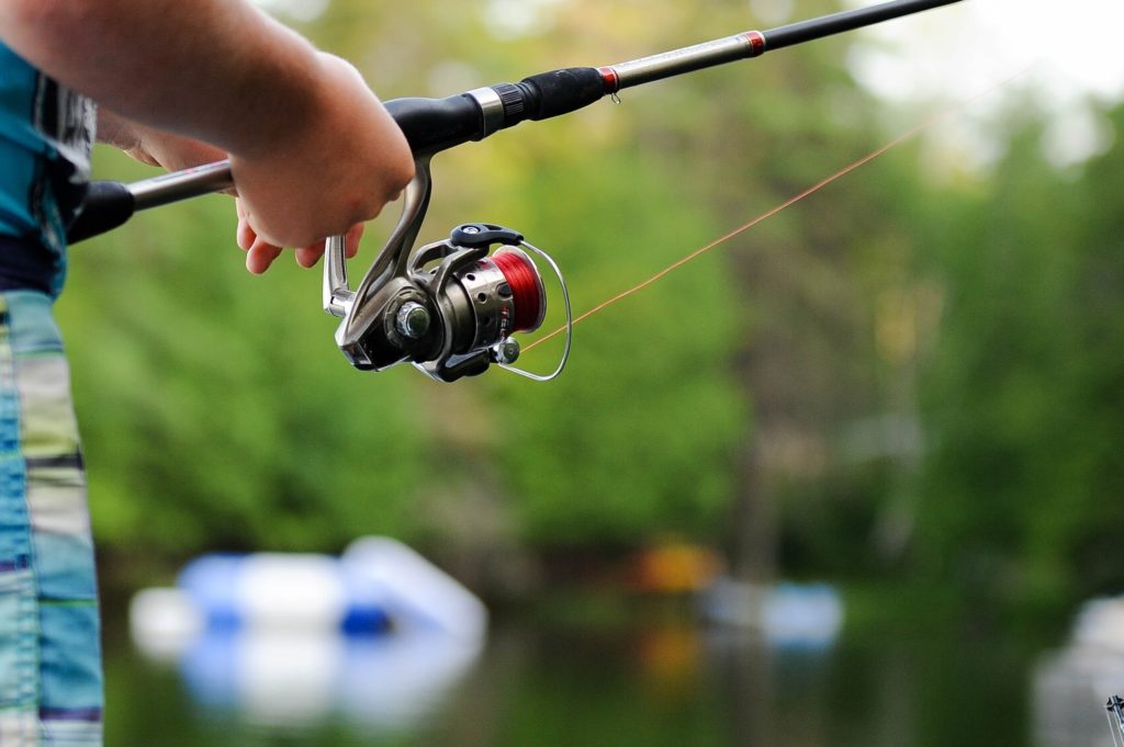 A person holding a fishing reel at a local waterway fishing spot.