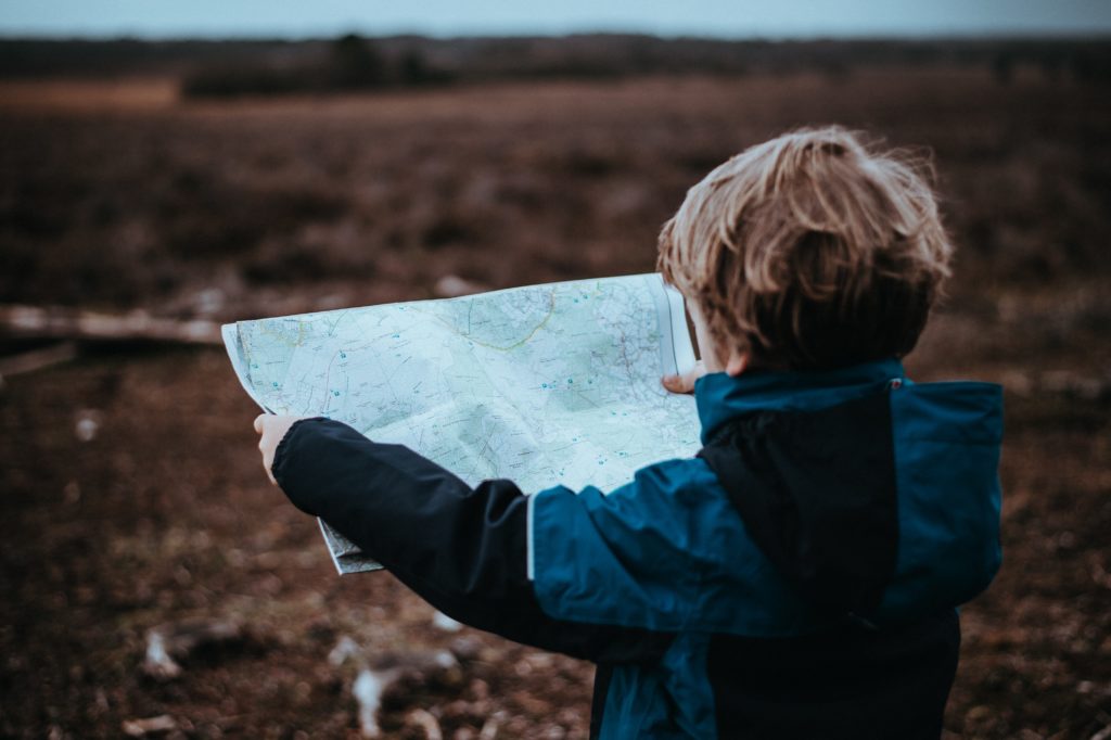 A child standing outside while looking at a topographical map of the surrounding area.