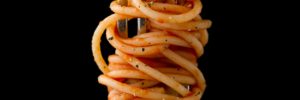 A fork full of spaghetti in a marinara sauce.