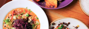 Several plates of vibrant and colorful plant-based and 'raw' dishes.