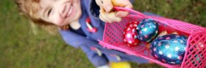 A young girl with a pink basket full of chocolate eggs.