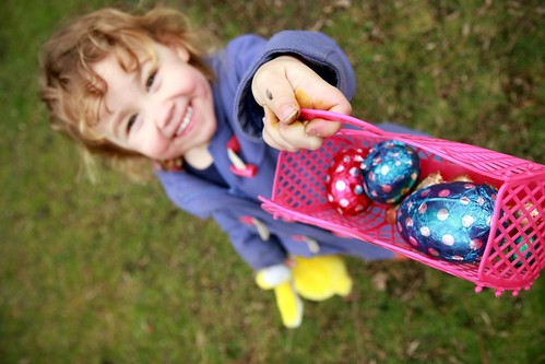 A young girl with a pink basket full of chocolate eggs.