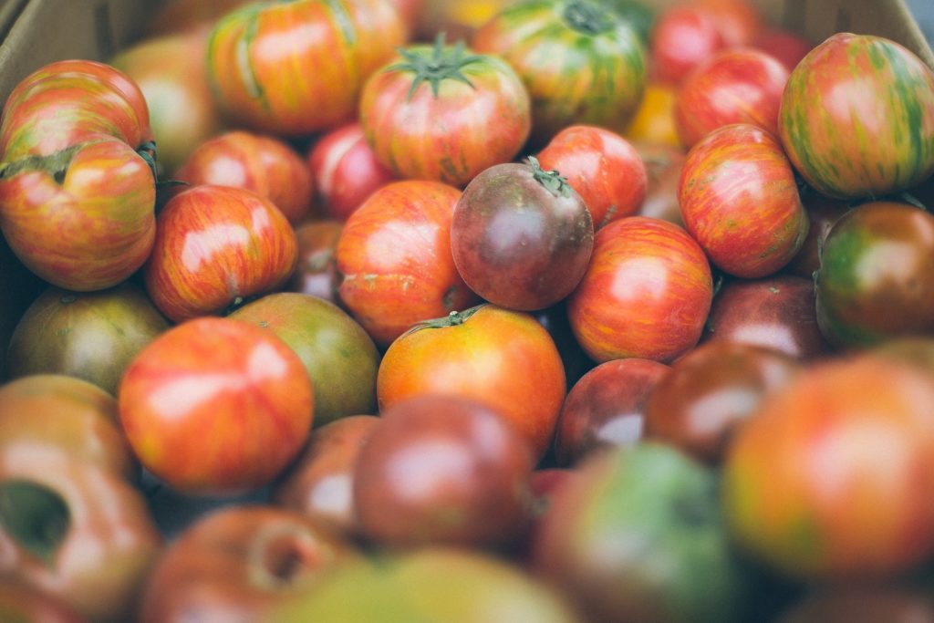 A close-up of a bin full of fresh heirloom tomatoes.