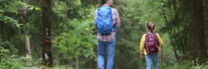 A father and daughter walking down a forest trail.