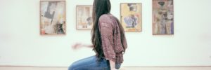 A woman sitting on a bench in an art gallery, observing the pieces on display.
