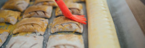 A person brushing eggs on pastries in a kids cooking class in Port Potomac, VA