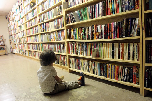 A child sitting on the floor looking at a bookshelf at a bookstore in Chicago, IL