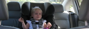 A young girl sits in her car seat in her parent's car