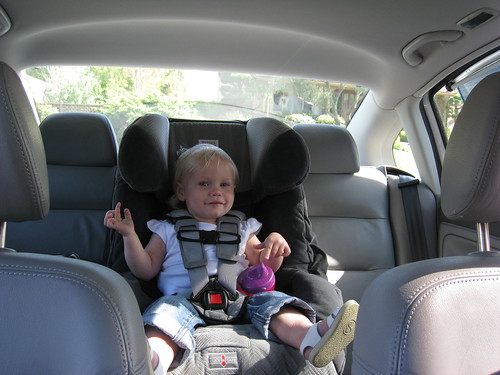 A young girl sits in her car seat in her parent's car