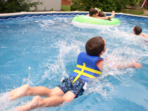 A young boy swims in a pool with his lifejacket
