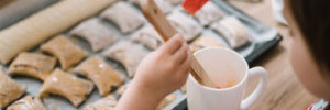 A young child spreads butter on pastries at a kids cooking class near Atlanta, GA