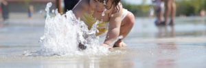 A young girl plays at a fountain in a splash pad in Centennial, CO