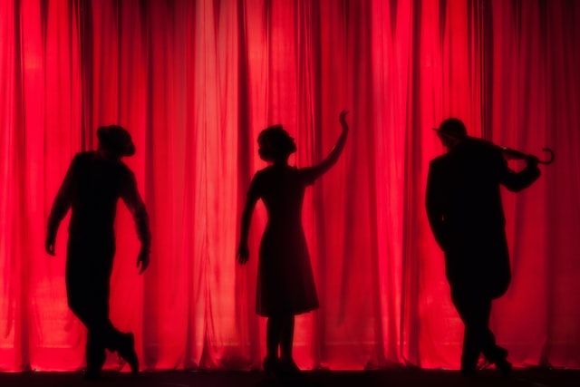Three performers wait behind the curtain at a theater near Fishers, IN