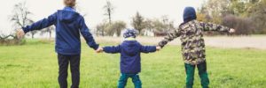 Three children hold hands at a park reserve in Maple Grove, Minnesota