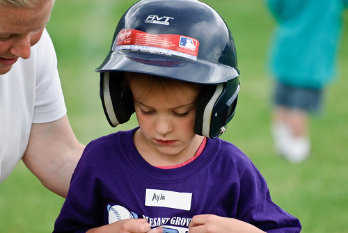 Kid playing baseball listening to adult
