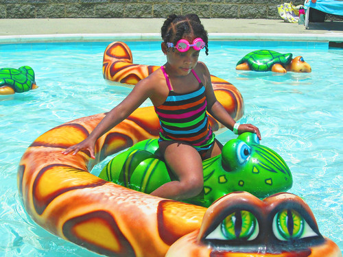 A young girl uses a frog shaped floaty at the aquatic center in Gilbert, Arizona
