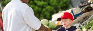 A young boy and a man greet each other at a farmers market in Deerfield Township, Ohio