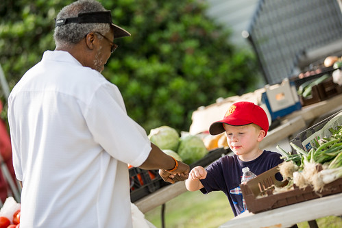 A young boy and a man greet each other at a farmers market in Deerfield Township, Ohio
