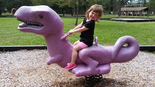A young girl plays on a purple dinosaur at a park in Buckhead, Georgia