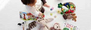 A child sits on a blanket with her toys during therapeutic playtime