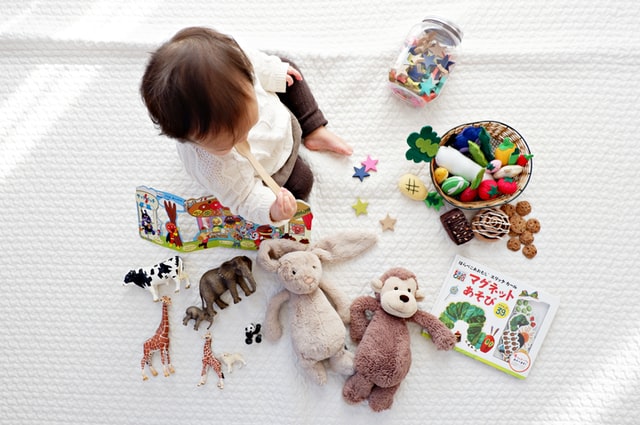 A child sits on a blanket with her toys during therapeutic playtime