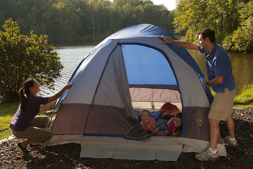 Image of a family setting up a blue camping tent.