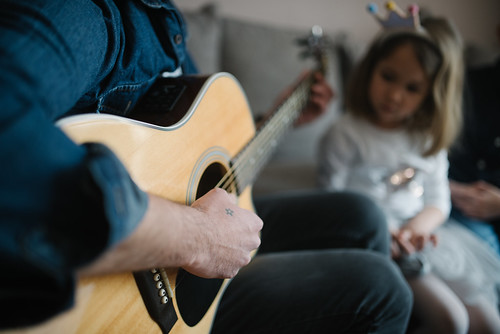 Man playing a guitar for a small child.