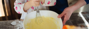 Photo of a child stirring a batter with a whisk.