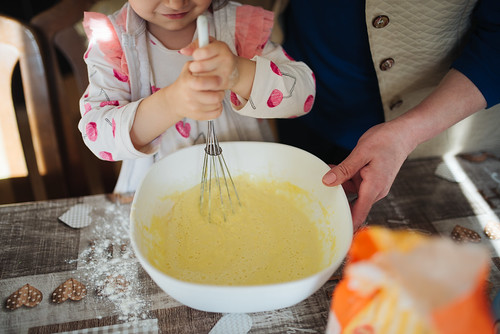 Photo of a child stirring a batter with a whisk.