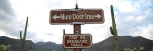 Landscape image of Mule Deer Trail Sign with a desert in the background.