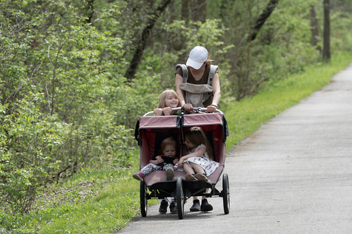 Woman walking with her three kids in a stroller.