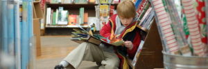 Small boy reading a book in a book store.