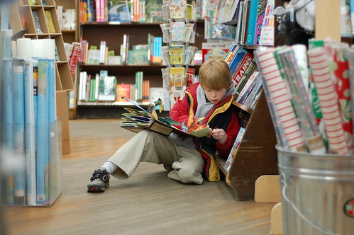 Small boy reading a book in a book store.